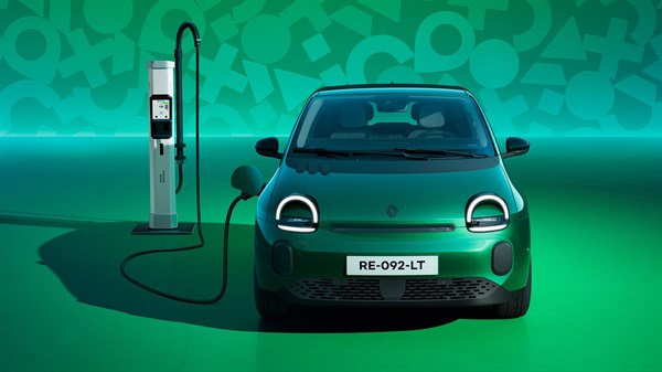 Zeleni Renault Twingo E-Tech electric prikazan sprijeda uz punionicu u zelenom studijskom prostoru.