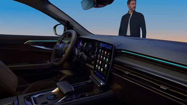 Pogled iz unutrašnjosti vozila Renault Austral full hybrid E-Tech prema muškarcu ispred vozila, uz prikaz središnjeg zaslona.

