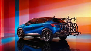 Renault Captur u stražnjem tričetvrtinskom pogledu u studijskom okruženju s narančasto-crvenim pozadinama, s nosačem i biciklima na stražnjem dijelu te odrazom na sjajnoj podlozi.