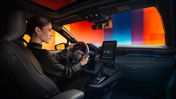 Vozačica upravlja vozilom u modernom interijeru, u šareno osvijetljenom ambijentu za Renault Captur full hybrid E-Tech.