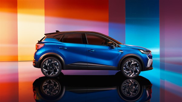 Captur full hybrid E-Tech u profilu, u plavoj boji, na šarenoj podlozi ispred raznobojnih panela.