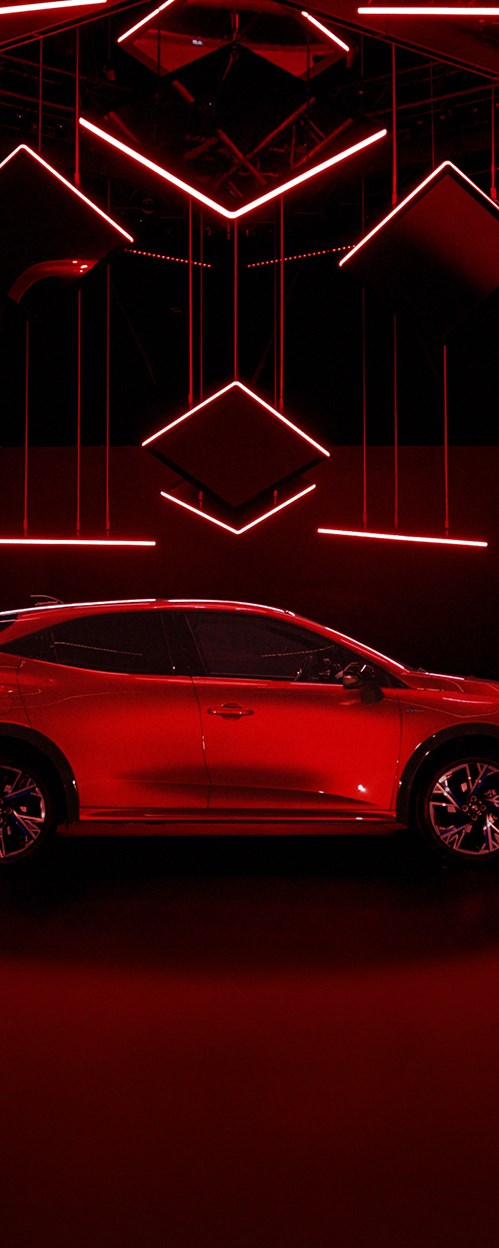 Bočni pogled na crveni Renault Cliou tamnom izložbenom prostoru, osvijetljen crvenim LED svjetlima.