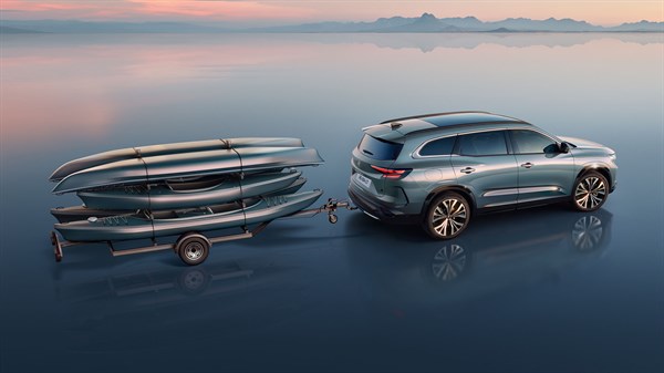 Vozilo Espace full hybrid E-Tech s prikolicom na kojoj se nalaze kajaci, parkirano na ravnoj površini u mirnom krajoliku.