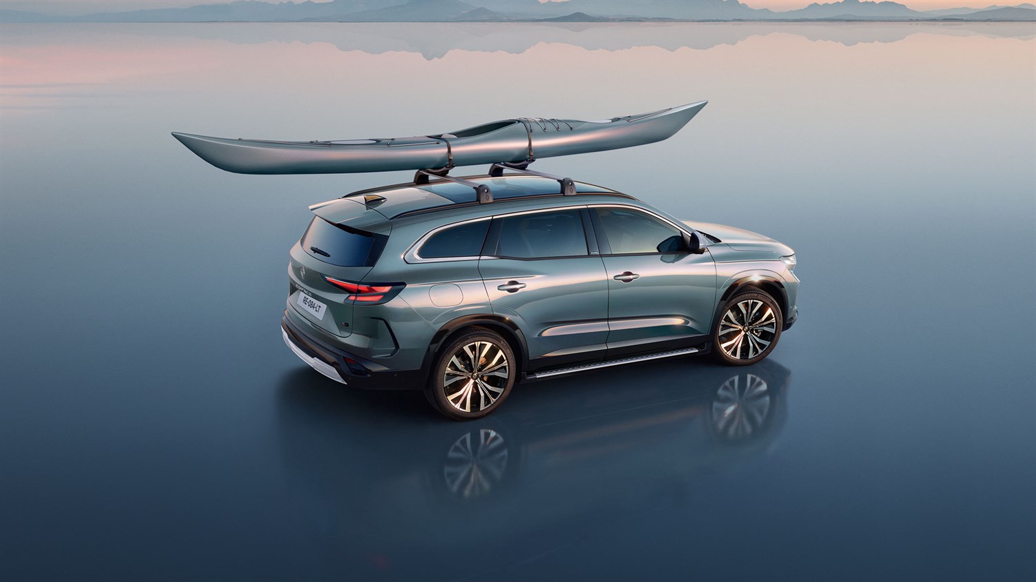 Renault Espace full hybrid E-Tech na mirnoj površini s kajakom pričvršćenim na krovne nosače.

