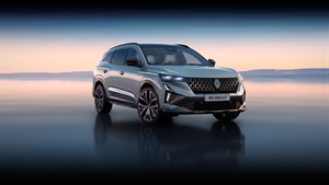 Stražnji bočni pogled na vozilo Renault Espace full hybrid E-Tech parkirano uz vodenu površinu pri zalasku sunca.

