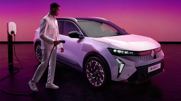 Prednji dio bijelog Renault Scenic E-Tech electric vozila spojenog na punionicu, snimljen u ambijentu toplih ružičastih i ljubičastih tonova.