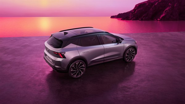 Renault Scenic prikazan sprijeda u tričetvrtinskom pogledu na tamnoj podlozi, uz ružičasto-ljubičasto nebo u pozadini.