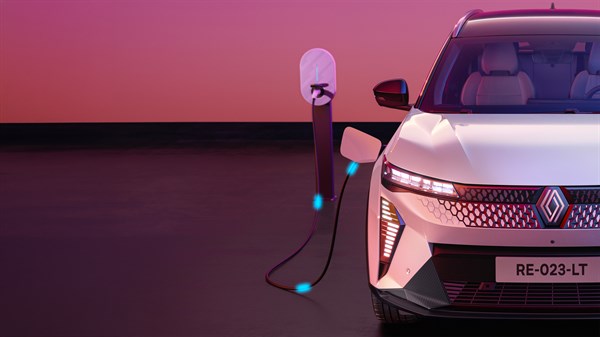 Renault Scenic prikazan sprijeda uz priključak za punjenje, s električnim kabelom i simboličnim prikazom energije na ružičasto-ljubičastoj pozadini.
