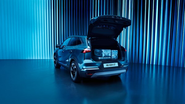 vozilo Renault Symbioz s otvorenim prtljažnikom, prikaz organiziranog prostora za prtljagu s koferima i dječjim kolicima, plava pozadina

