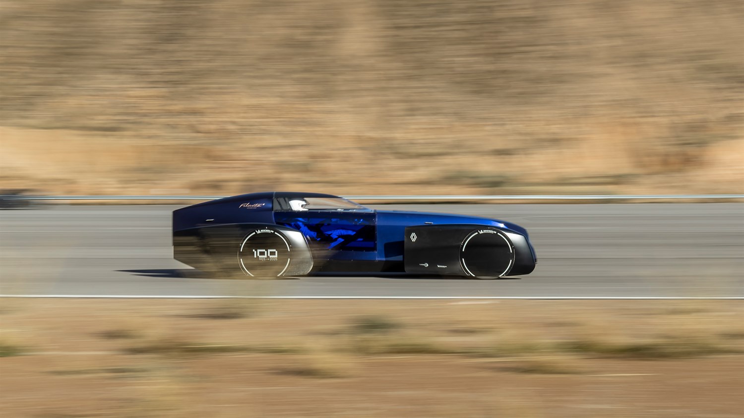 Renault Filante futurističko električno vozilo u plavoj boji snimljeno u bočnom profilu tijekom vožnje po testnoj stazi, s naglašenim aerodinamičnim oblikom i minimalističkim kotačima.
