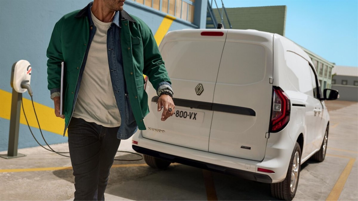 muškarac hoda pokraj parkiranog vozila Kangoo Van E-Tech electric koje se puni na vanjskoj punionici, stražnji prikaz vozila