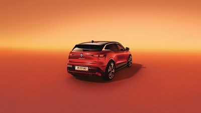 Crveni Renault Megane E-Tech electric parkiran ispred narančaste pozadine u zalasku sunca.