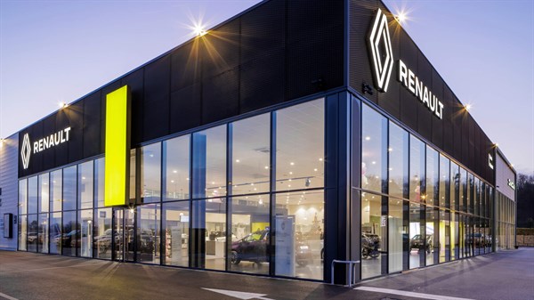 Renault salon u sumrak s osvijetljenim logotipima i velikim staklenim izlogom.