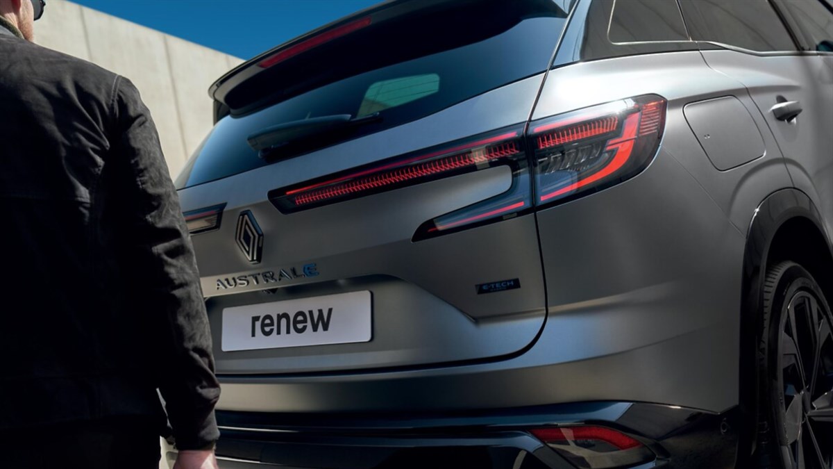 Dvije žene u živopisnoj odjeći stoje ispred plavog vozila Renault Captur ispred zgrade s neonskim znakom.








